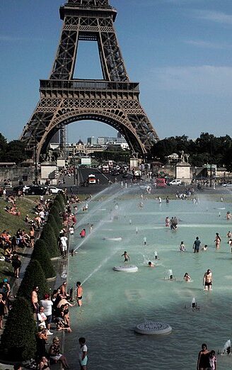 People swim in the Seine River in front of the Eiffel Tower on a hot summer day.
