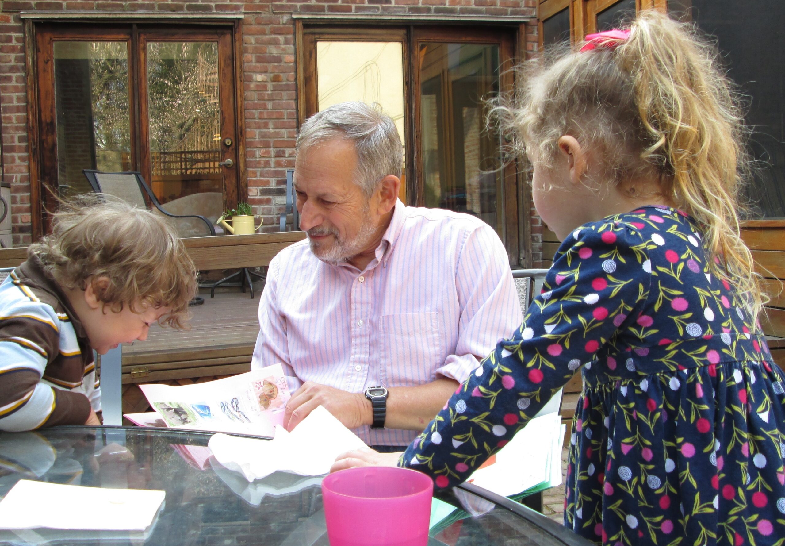 Dr. Mark Cane poses with his two grandkids as they look at some pieces of paper