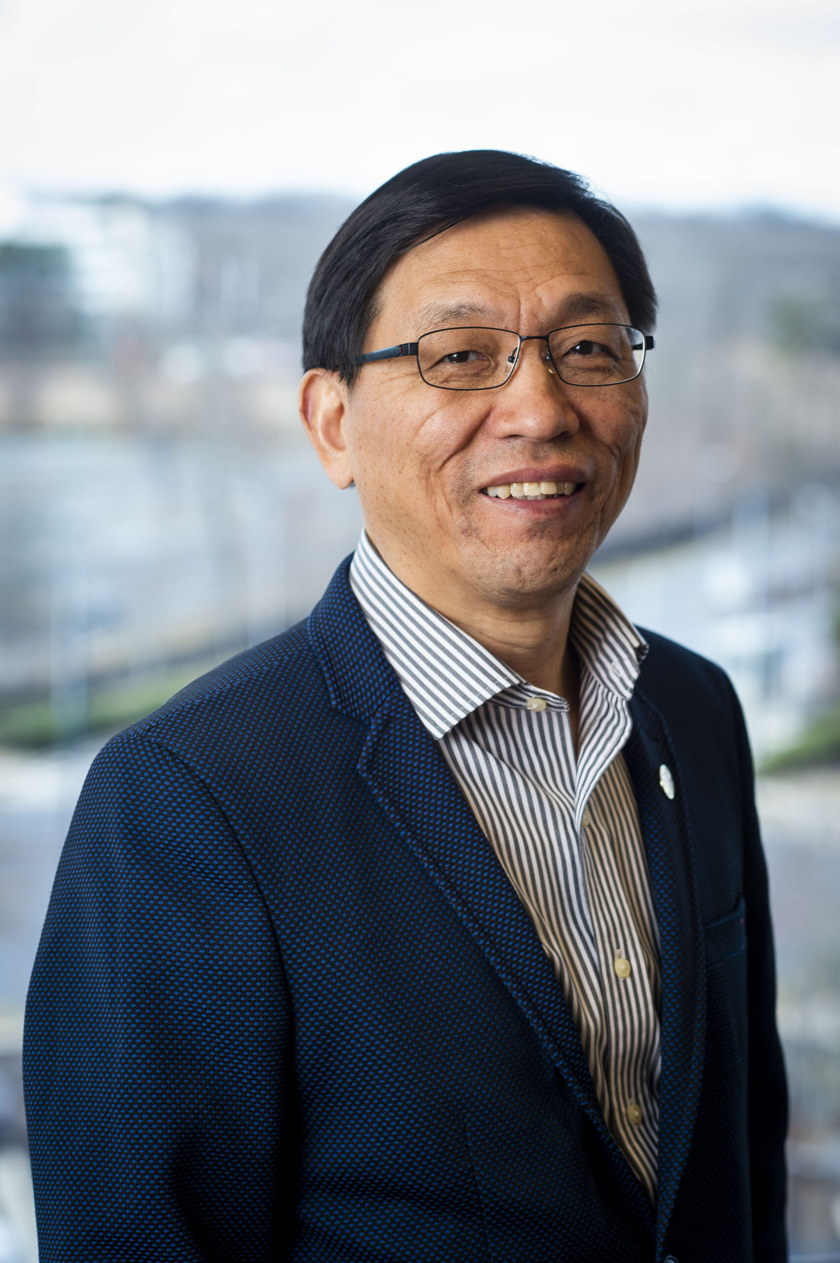 Dr. Zhanqing Li smiles in a suit in front of a blurry background