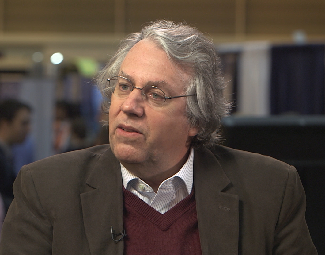 A shot of Dr. Kerry Emanuel mid-conversation, wearing wire-framed glasses and a smart outfit