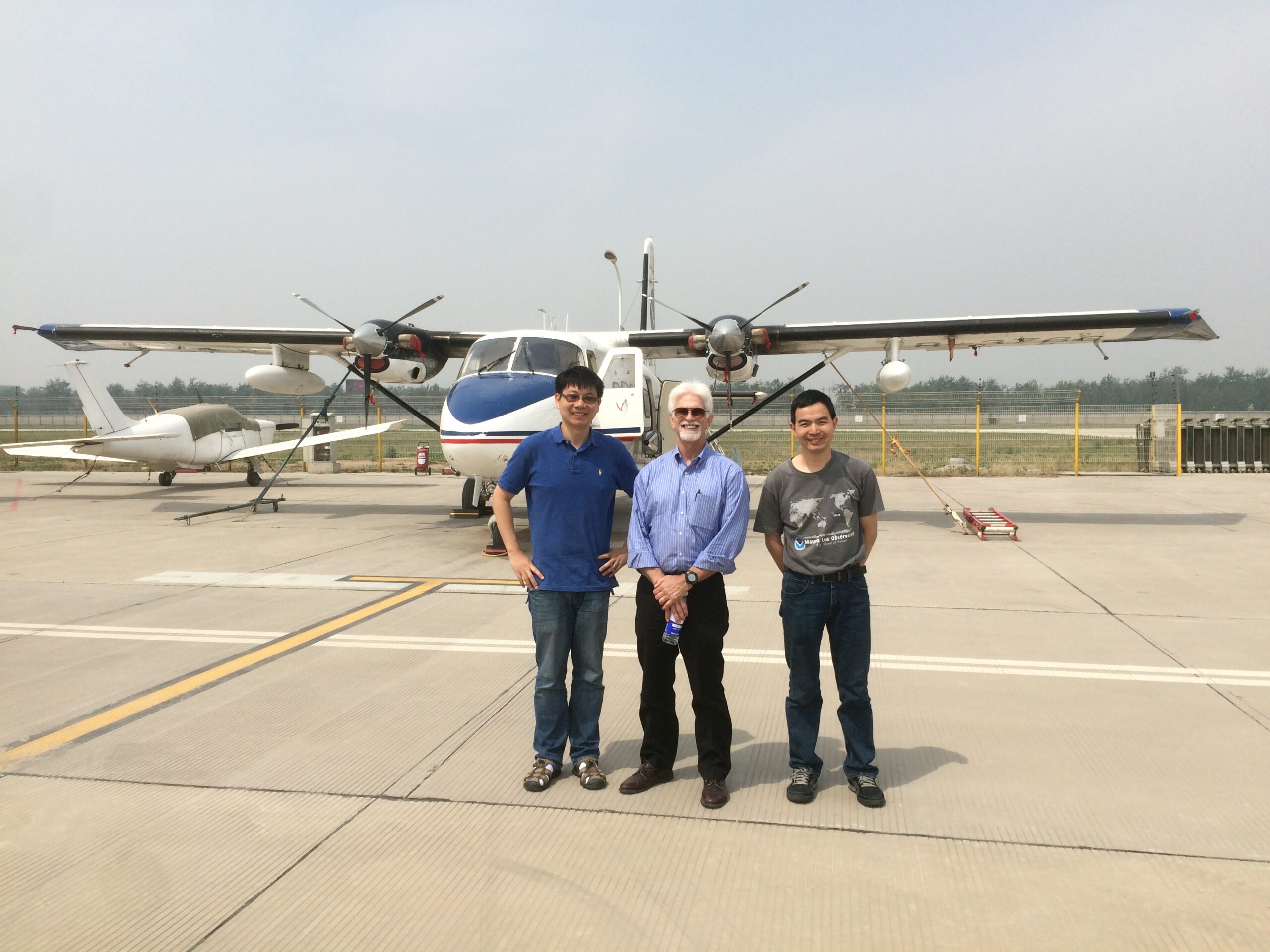 The researchers smile in front of a plane